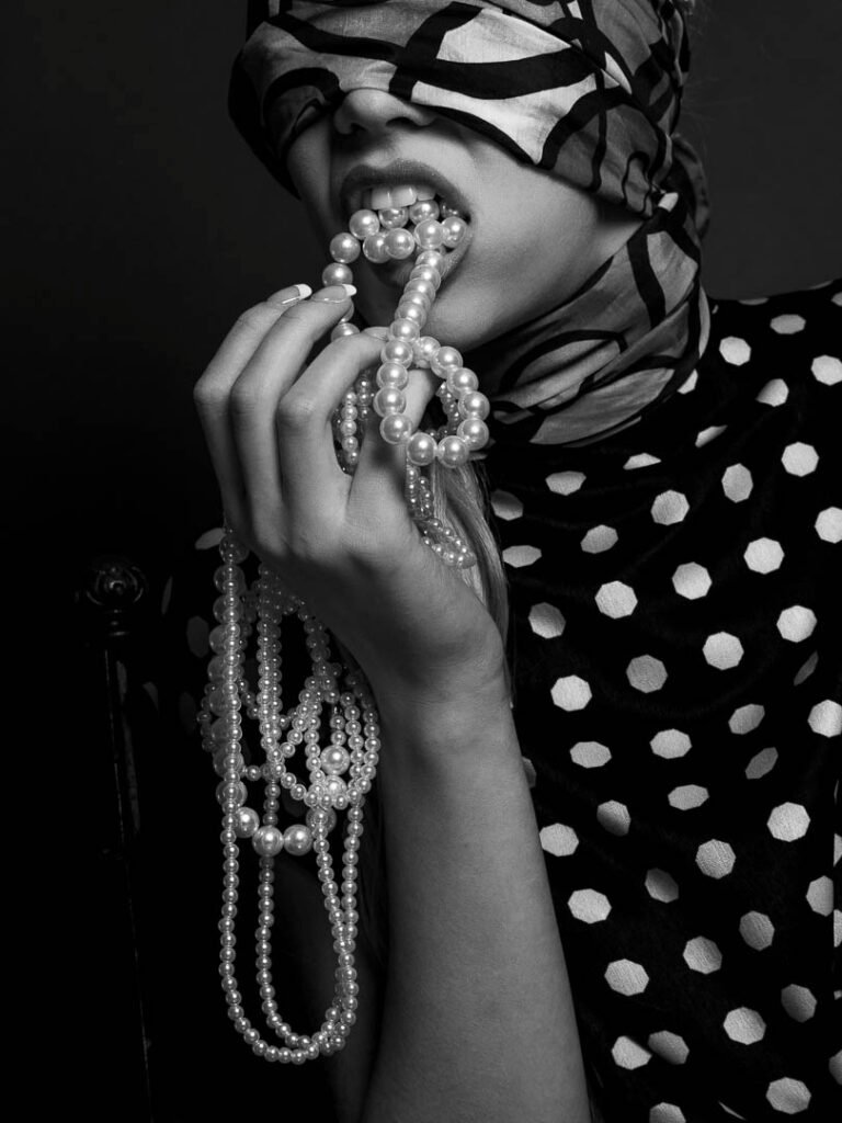 A model eating a pearl necklace, illustrating the impact of GLP-1 drugs into the fashion industry.